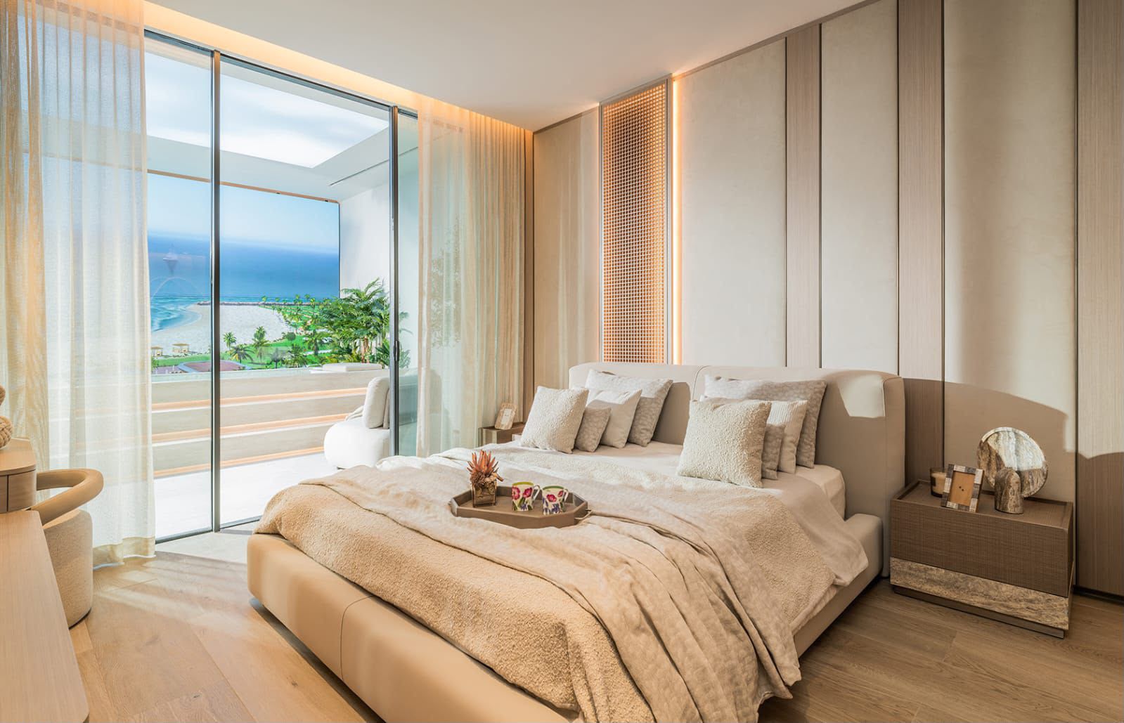 One-bedroom interior with an upholstered bed and glazing to a sea-view terrace